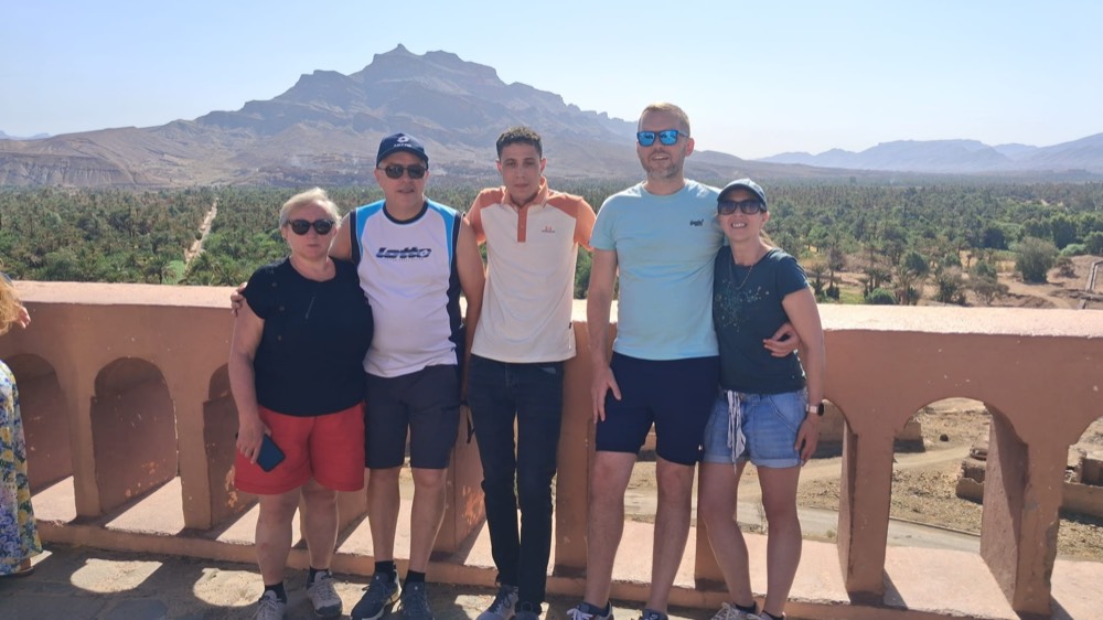 Guests on a terrace above a palm valley with a mountain behind