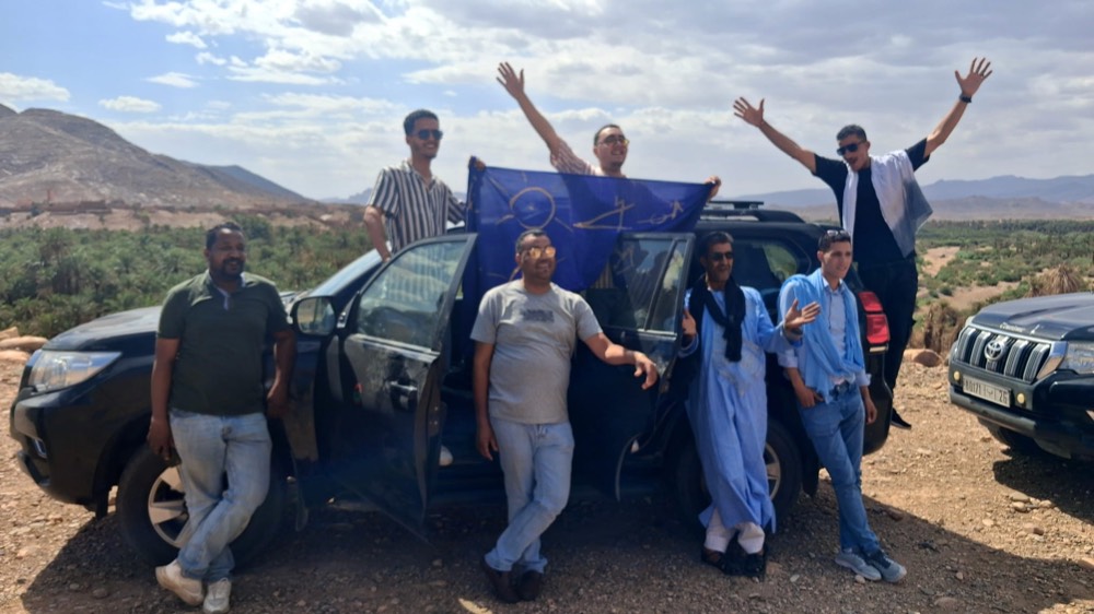 A group beside two Land Cruisers on a track above an oasis