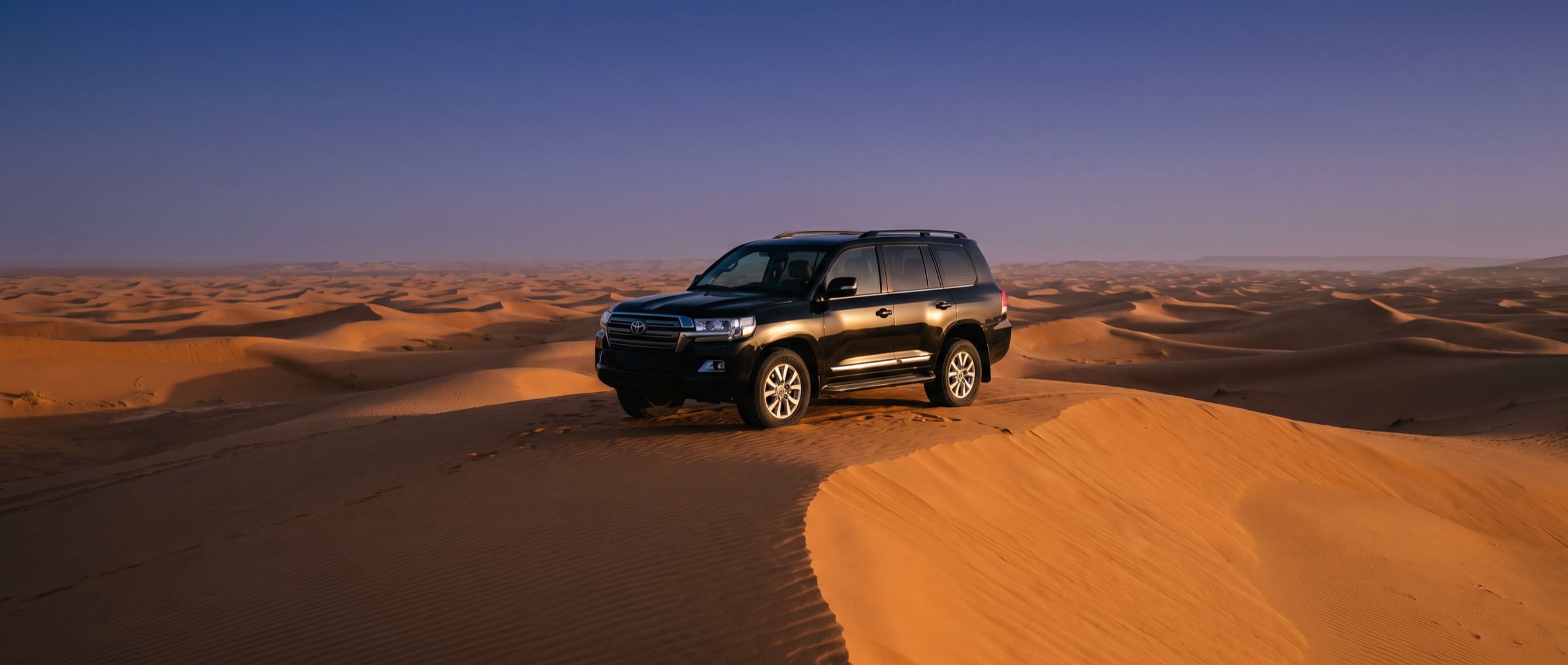 A Land Cruiser on a dune crest in Erg Chegaga at sunset